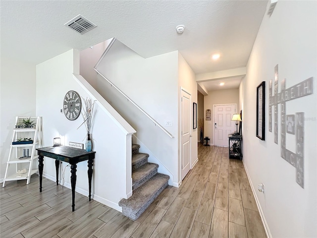 staircase with a textured ceiling and hardwood / wood-style flooring