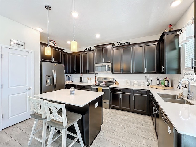 kitchen with sink, a center island, pendant lighting, dark brown cabinets, and appliances with stainless steel finishes