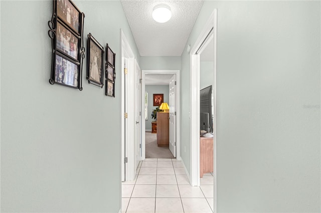 corridor with light tile patterned flooring and a textured ceiling