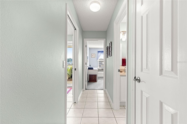 corridor with light tile patterned floors and a textured ceiling