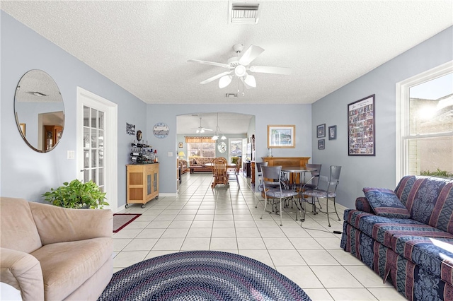 living room with a textured ceiling, ceiling fan, and light tile patterned flooring