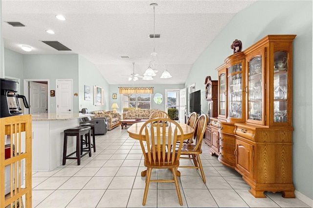 tiled dining room with a textured ceiling, ceiling fan, and vaulted ceiling