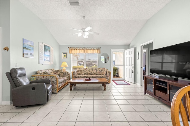 living room with ceiling fan, lofted ceiling, a textured ceiling, and light tile patterned floors