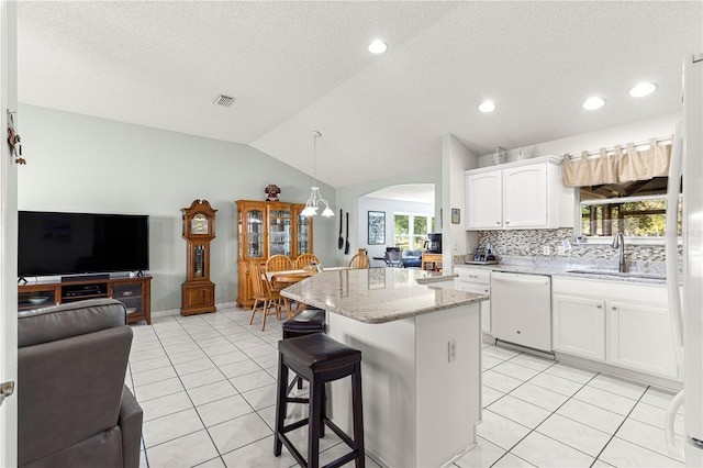 kitchen featuring dishwasher, sink, decorative light fixtures, vaulted ceiling, and white cabinets