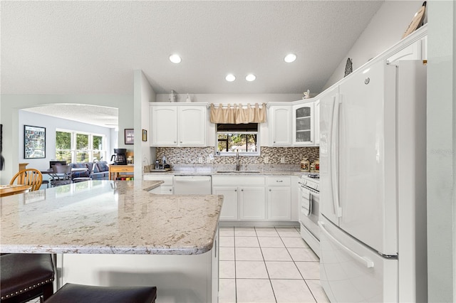 kitchen with plenty of natural light, white cabinets, white appliances, and sink