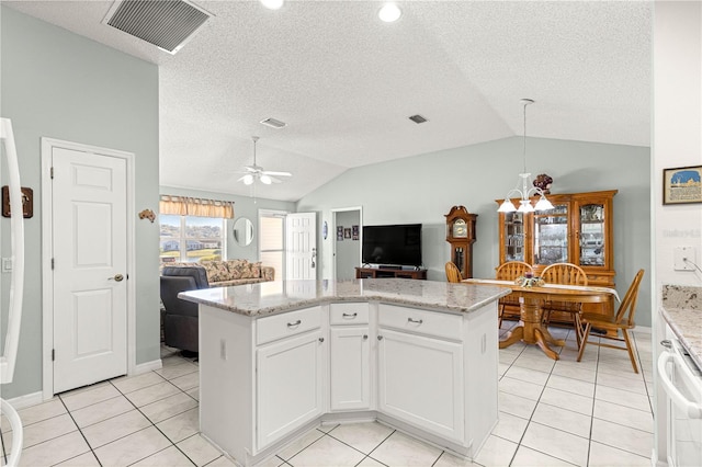 kitchen featuring light stone countertops, ceiling fan with notable chandelier, white cabinets, a kitchen island, and lofted ceiling