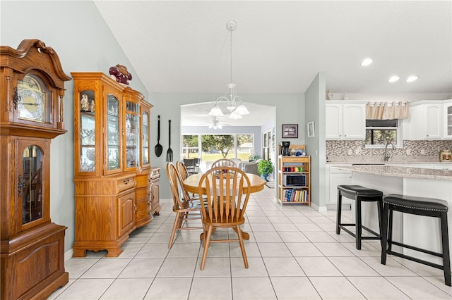 tiled dining area with sink, vaulted ceiling, and an inviting chandelier