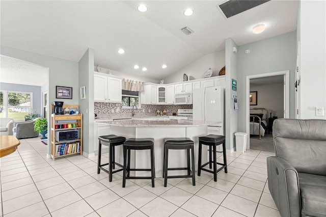 kitchen with a breakfast bar area, a center island, white cabinets, and white appliances