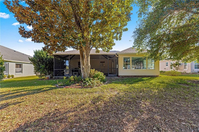 rear view of property featuring a sunroom and a yard