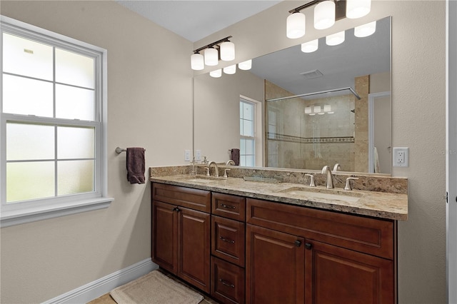 full bath featuring double vanity, a shower stall, baseboards, and a sink