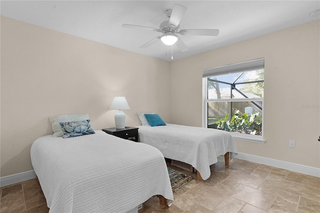 bedroom featuring stone finish floor, a ceiling fan, and baseboards