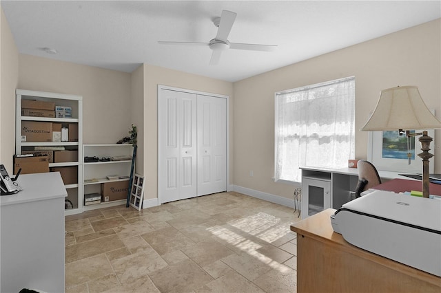 office area featuring ceiling fan, stone finish floor, and baseboards