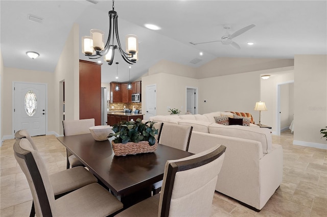 dining area with lofted ceiling, baseboards, and ceiling fan with notable chandelier