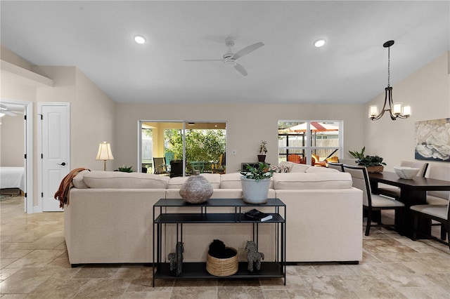 living area featuring lofted ceiling, recessed lighting, a wealth of natural light, and ceiling fan with notable chandelier