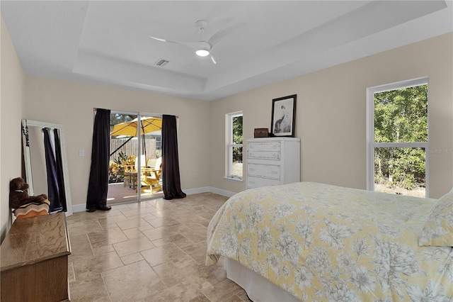 bedroom with a ceiling fan, visible vents, baseboards, stone finish flooring, and a raised ceiling