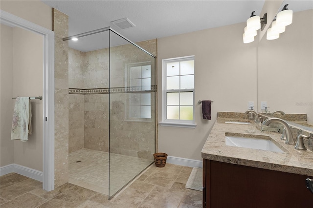 bathroom featuring visible vents, a sink, baseboards, and a walk in shower