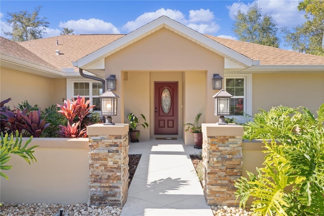 property entrance featuring roof with shingles and stucco siding