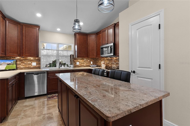 kitchen featuring a sink, appliances with stainless steel finishes, a kitchen island, and tasteful backsplash