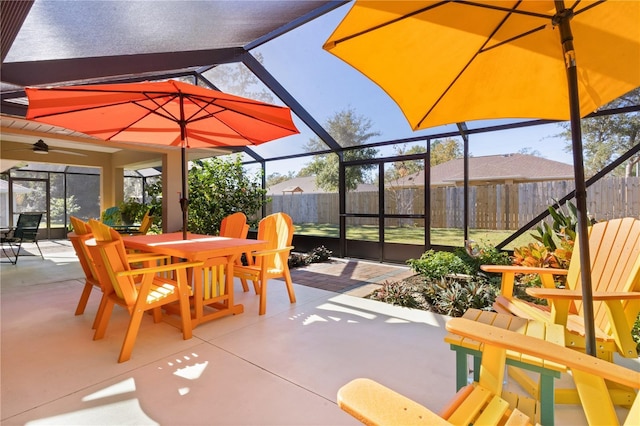 view of patio / terrace featuring glass enclosure, ceiling fan, fence, and outdoor dining area