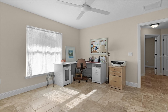 office featuring ceiling fan, stone finish flooring, visible vents, and baseboards