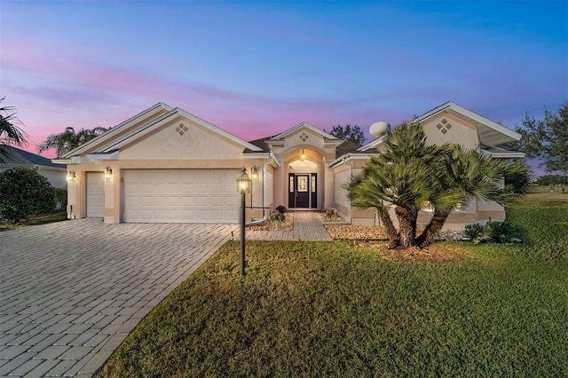 ranch-style home with a garage and a lawn