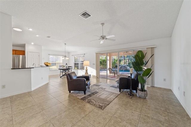 tiled living room with a healthy amount of sunlight, ceiling fan with notable chandelier, and a textured ceiling