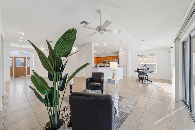 living room with ceiling fan with notable chandelier, a textured ceiling, and light tile patterned floors