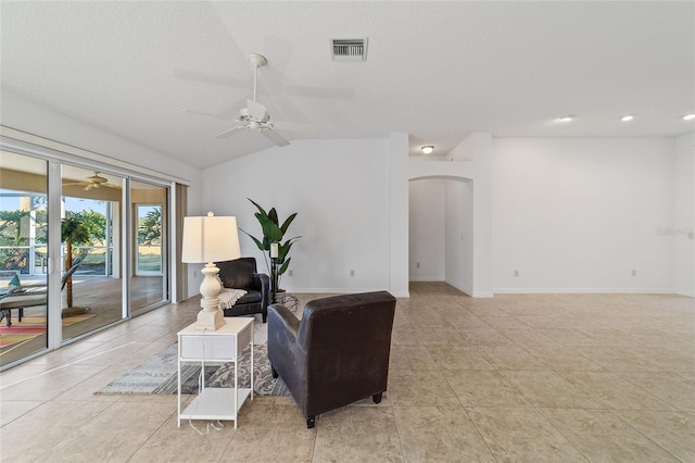 tiled living room with ceiling fan, vaulted ceiling, and a textured ceiling