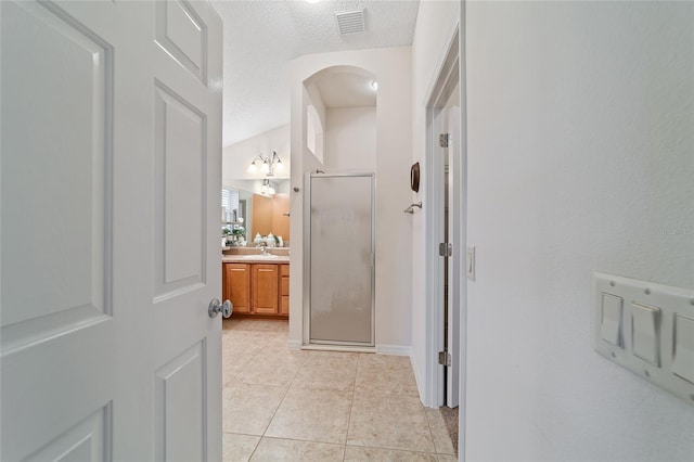 corridor featuring sink, light tile patterned floors, and a textured ceiling