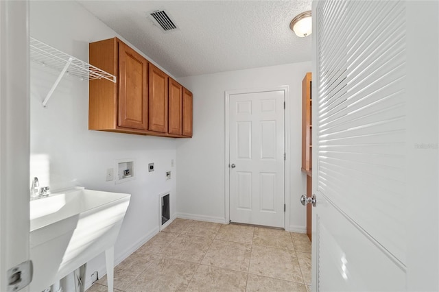 clothes washing area with hookup for a washing machine, cabinets, a textured ceiling, light tile patterned flooring, and hookup for an electric dryer