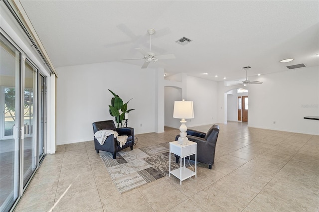 living area with lofted ceiling, light tile patterned floors, a textured ceiling, and ceiling fan