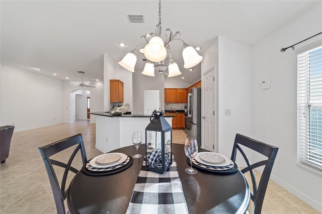 dining area featuring ceiling fan with notable chandelier, lofted ceiling, light tile patterned floors, and a textured ceiling