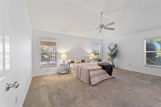 carpeted bedroom with multiple windows, ceiling fan, vaulted ceiling, and a textured ceiling