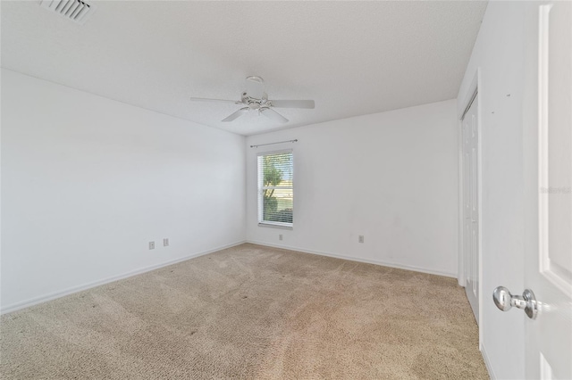 unfurnished room featuring ceiling fan, light colored carpet, and a textured ceiling