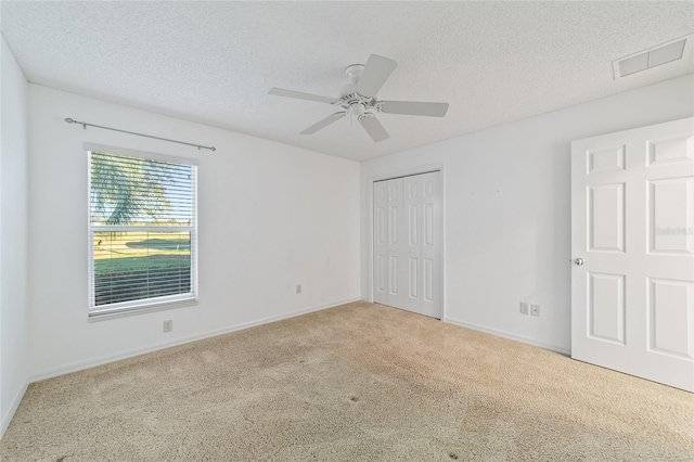 unfurnished bedroom featuring ceiling fan, light colored carpet, a textured ceiling, and a closet