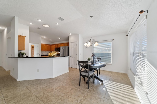 kitchen featuring lofted ceiling, an inviting chandelier, appliances with stainless steel finishes, kitchen peninsula, and pendant lighting