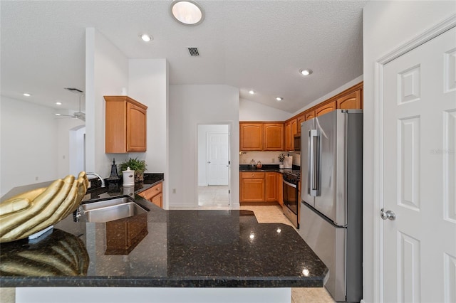 kitchen with lofted ceiling, sink, dark stone countertops, kitchen peninsula, and stainless steel appliances