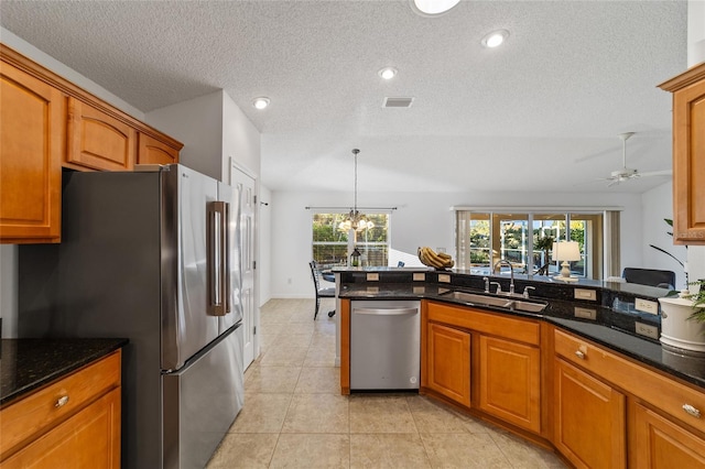 kitchen featuring stainless steel appliances, hanging light fixtures, sink, and dark stone counters