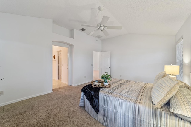 bedroom with lofted ceiling, light colored carpet, a textured ceiling, and ceiling fan