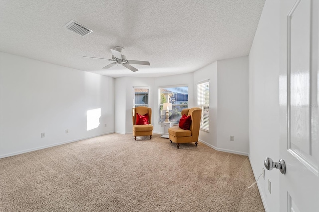 unfurnished room with a textured ceiling, ceiling fan, and carpet