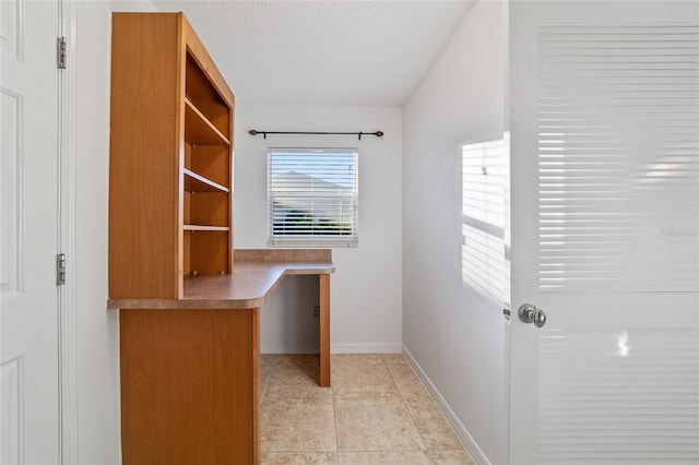 tiled home office featuring built in desk and a textured ceiling