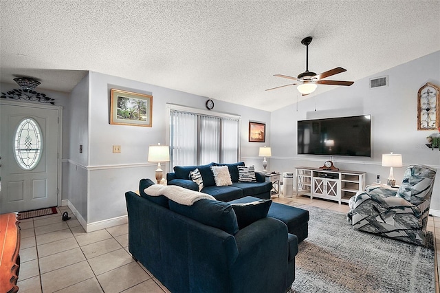 living room featuring a textured ceiling, ceiling fan, light tile patterned floors, and vaulted ceiling