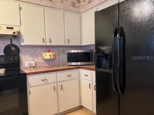 kitchen featuring black appliances, white cabinetry, backsplash, and range hood