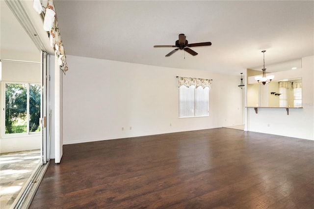 unfurnished living room with ceiling fan with notable chandelier and dark hardwood / wood-style flooring