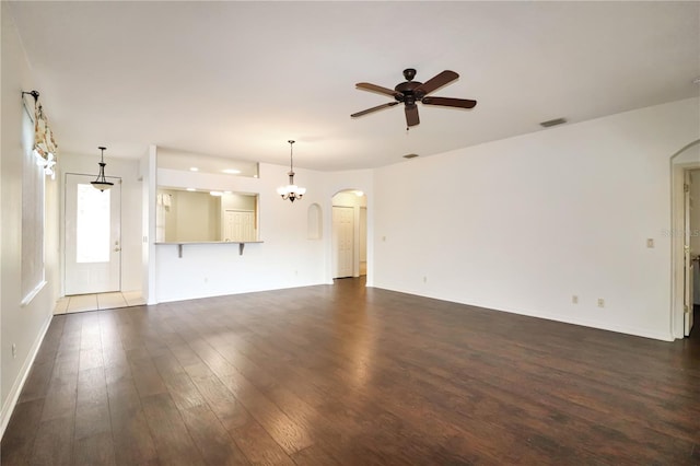 unfurnished living room with ceiling fan with notable chandelier and dark hardwood / wood-style flooring