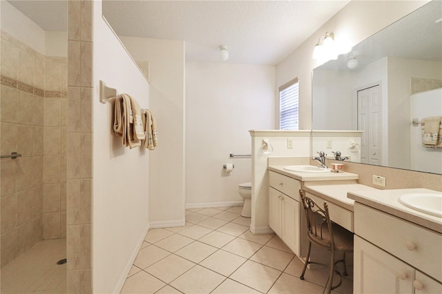 bathroom with vanity, tile patterned flooring, toilet, tiled shower, and a textured ceiling