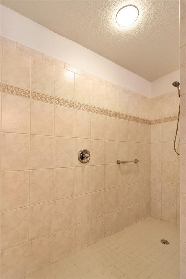 bathroom with a tile shower and a textured ceiling