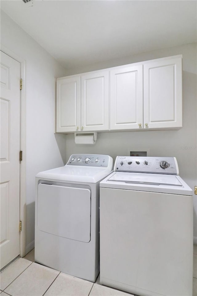 laundry area with light tile patterned flooring, cabinets, and separate washer and dryer