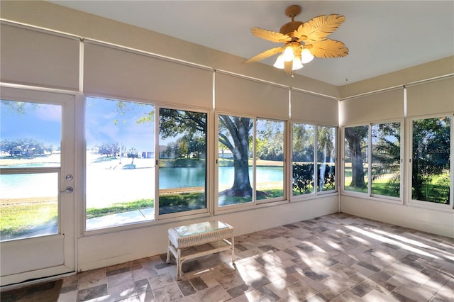 unfurnished sunroom with ceiling fan, a water view, and a healthy amount of sunlight