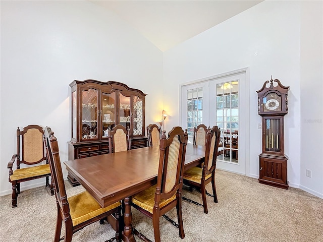 carpeted dining room featuring high vaulted ceiling